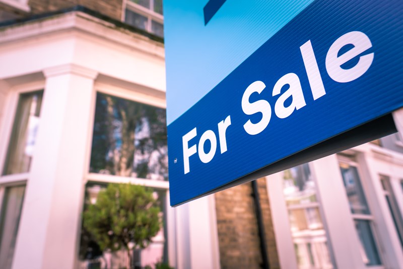 Estate agent For Sale sign on street of houses